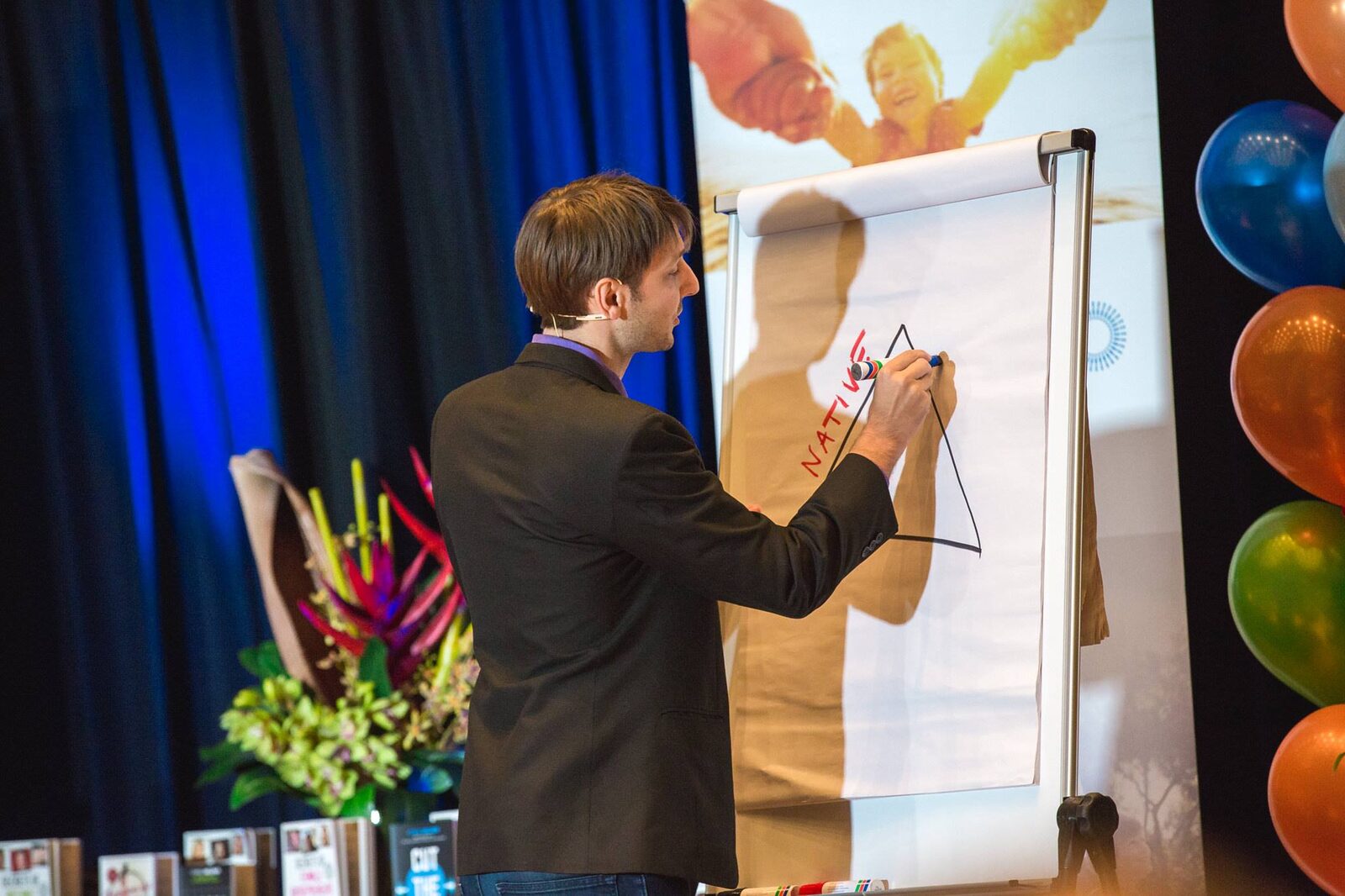 Carl Taylor teaching on a conference stage with a flip chart and marker
